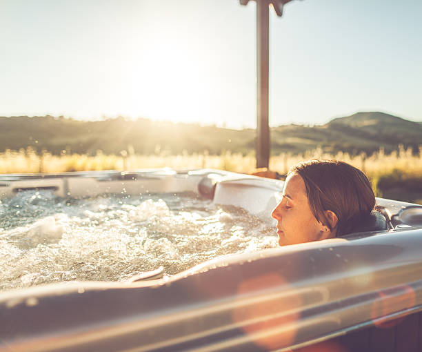 Woman in whirlpool hot tub Woman in whirlpool hot tub at sunset hot tub stock pictures, royalty-free photos & images