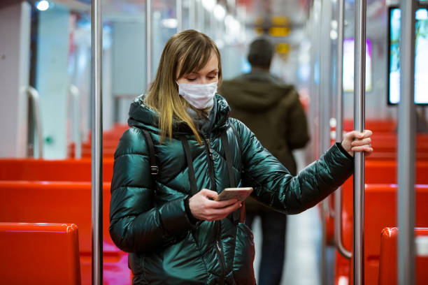 Woman in winter coat with protective mask on face standing in subway car stock photo