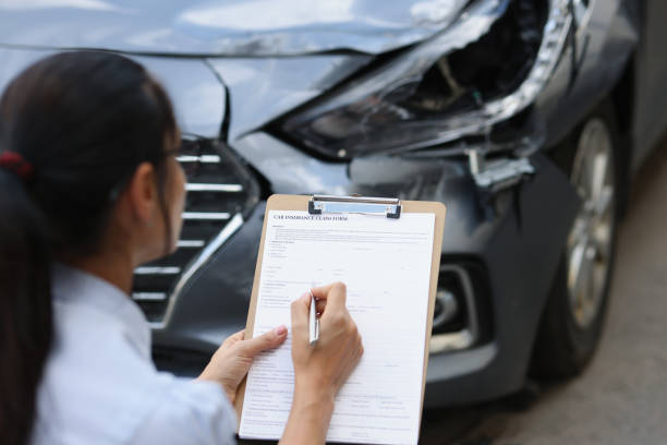 Woman insurance agent fills out insurance form for car damage after traffic accident stock photo