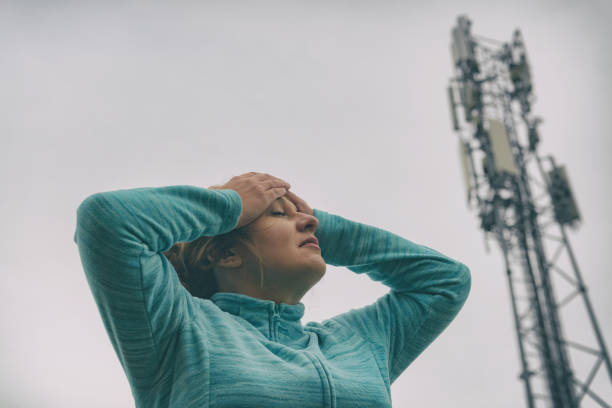 Woman is holding her head near the 5G BTS stock photo