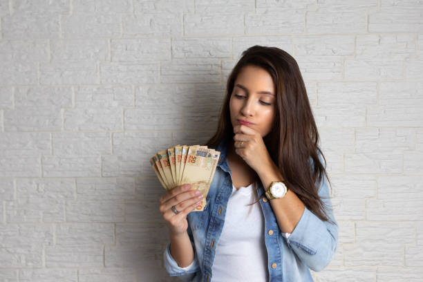 woman is looking at cash banknotes Young pretty woman is looking at cash banknotes, Brazil Currency. Financial, profit, credit, cost, purchase, rich concept. paper currency stock pictures, royalty-free photos & images