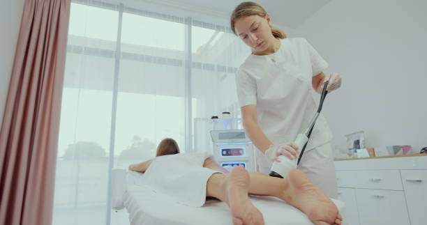 Woman is receiving the vacuum massage her legs and buttocks with LPG tool while lying in the spa salon. Burning body fat with machine cosmetology in healthcare concept.  vacuum butt lift stock pictures, royalty-free photos & images
