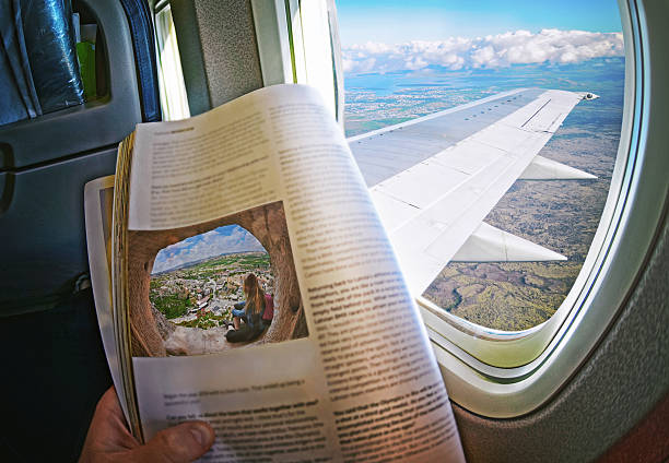 Woman is sitting   by window on a plane with magazine stock photo