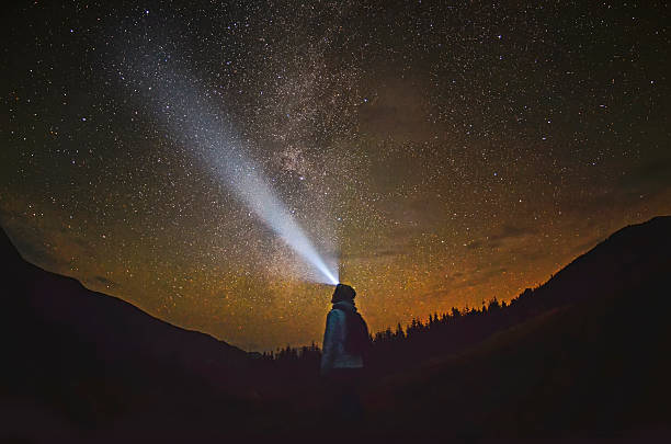 Woman is standing in the forest and pointing the Milky Way stock photo