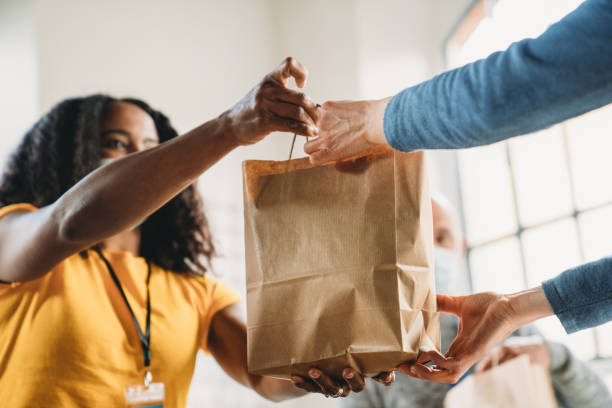 A woman is taking a paper bag of food at the food and clothes bank stock photo