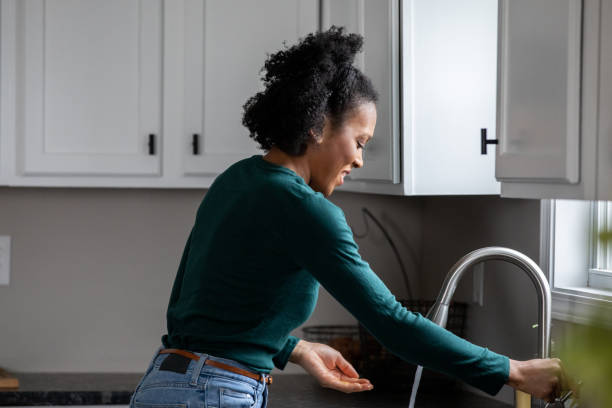 Woman is washing her hands at the kitchen sink stock photo