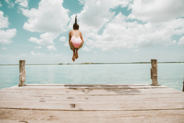 Woman jumping from pier Woman jumping from pier diving into water stock pictures, royalty-free photos & images