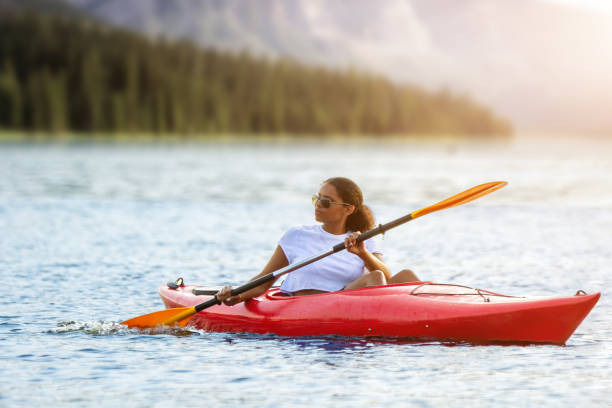 Woman kayaking on river alone with sunset on background stock photo