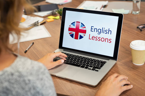 Woman learning english online Mature woman learning English online with computer at office. Laptop screen of woman displaying english lessons poster with British flag. Closeup of student using laptop doing online course on english. english language stock pictures, royalty-free photos & images