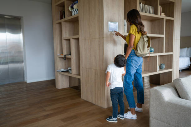 Woman leaving the house with her son and locking the door using a home automation system stock photo
