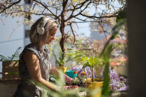 Woman listening to the music while potting plants stock photo