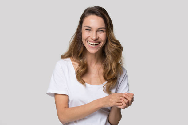 Woman looking at camera laughing feels happy studio shot Laughing millennial woman posing over white wall background looking at camera feels overjoyed happy, head shot portrait. Concept of positive news, rejoice facial expressions, having fun and happiness laughing stock pictures, royalty-free photos & images