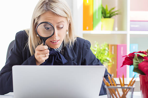 Woman looking at computer screen through a magnifying glass