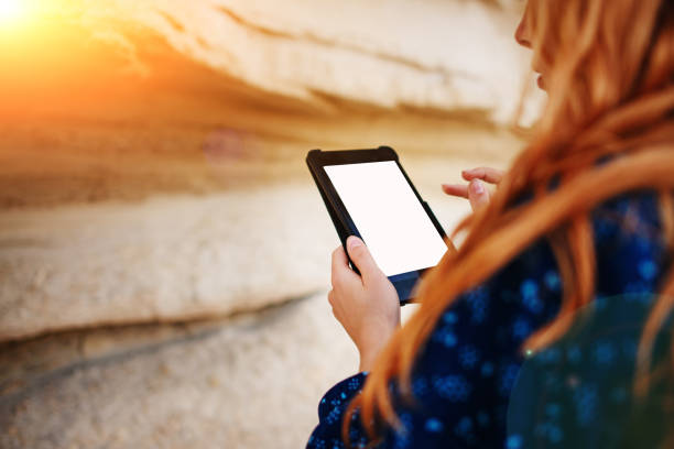 Woman looking at the screen of a tablet on the background of a sand quarry stock photo