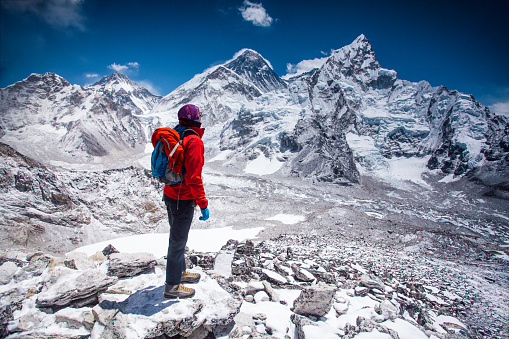 Woman standing on top of Kala Patthar summit on Himalayan range and looking at beautiful view with mt. Everest and lhotse