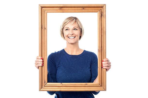 Woman looking through wooden frame stock photo