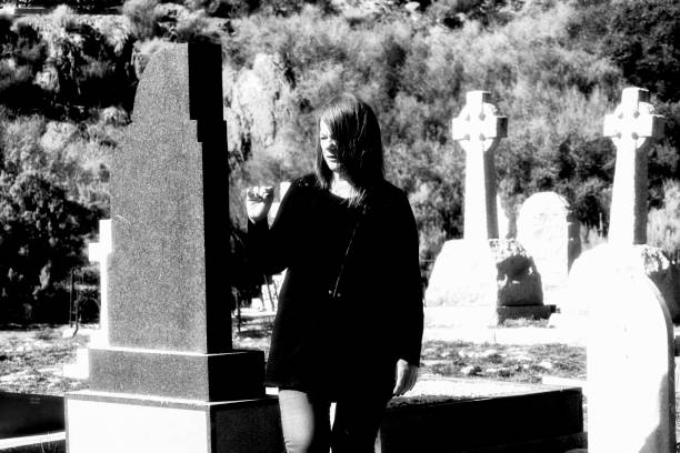 Woman looks at remote graves in a cemetery A woman dressed in black looks at old tomb stones in a cemetery memorial day background stock pictures, royalty-free photos & images