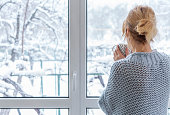 istock A woman looks out of the window at the snow-covered outdoors 1304149852