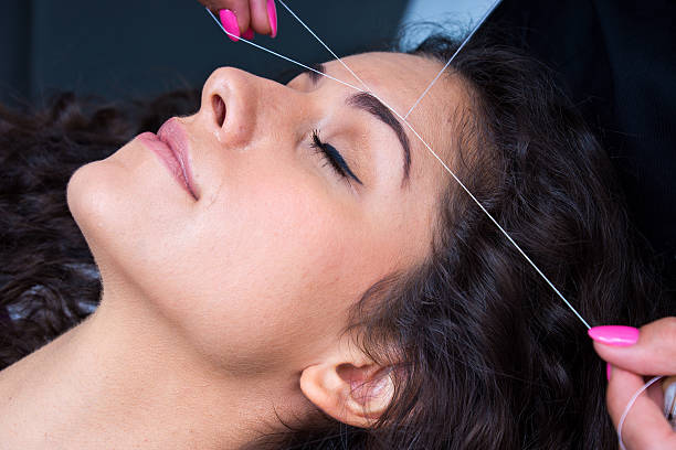Woman lying down having her eyebrows threaded  stock photo