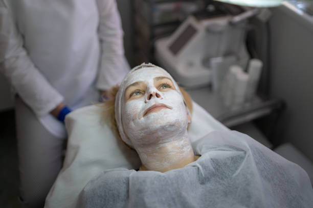 A woman lying down with a face mask on Visiting the beauty salon a woman is lying down wearing a white face mask treatment Hypopigmentation stock pictures, royalty-free photos & images