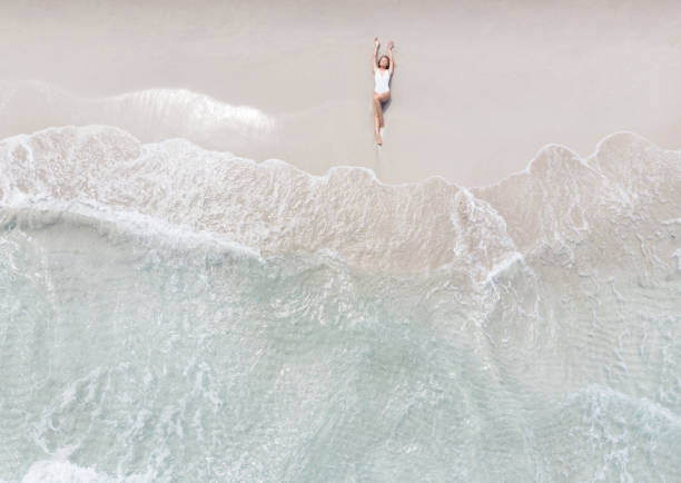 vrouw liggend op een strand - egeïsche zee stockfoto's en -beelden
