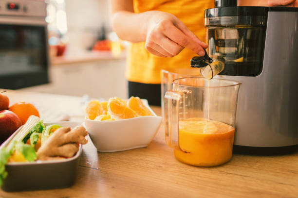 Woman making cold-pressed juice stock photo