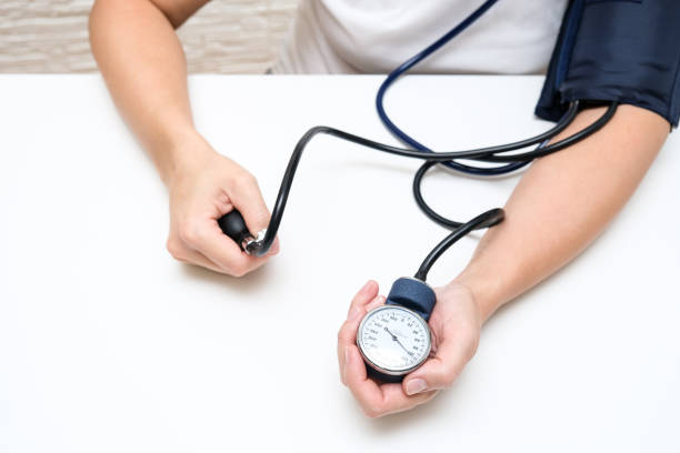 Woman measuring blood pressure by herself at home, pressure control to prevent heart cardiolvascular problems of people with high risk stock photo