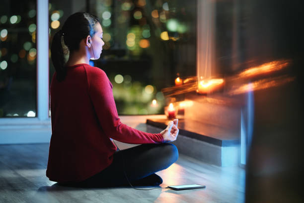 Woman Meditating At Night With Smartphone App For Yoga night yoga stock pictures, royalty-free photos & images