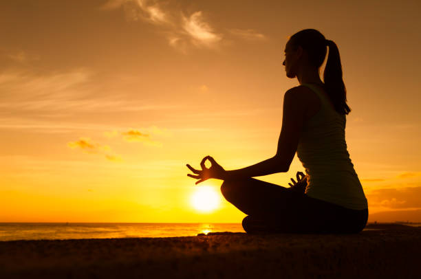 Woman meditating by the beach stock photo