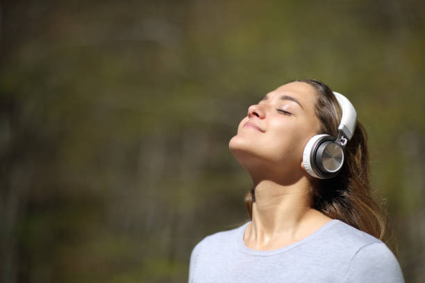femme méditant utilisant des écouteurs dans un stationnement - telecharger image gratuit photos et images de collection