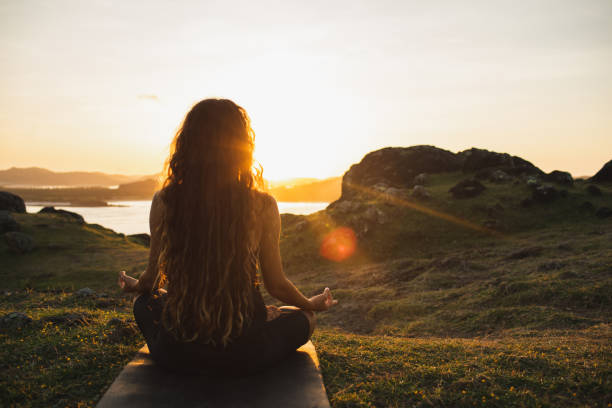 Woman meditating yoga alone at sunrise mountains. View from behind. Travel Lifestyle spiritual relaxation concept. Harmony with nature. stock photo