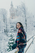 Schwangau, Germany - November 29, 2017: Young Caucasian woman walking in the park near Neuschwanstein castle in Germany in winter