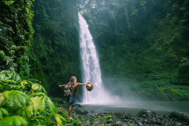 インドネシア・バリ島で水たびを実施する際に近くにいた女性 - 滝 ストックフォトと画像