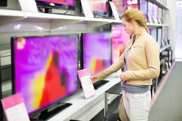 A woman observing prices for a television in a store stock photo