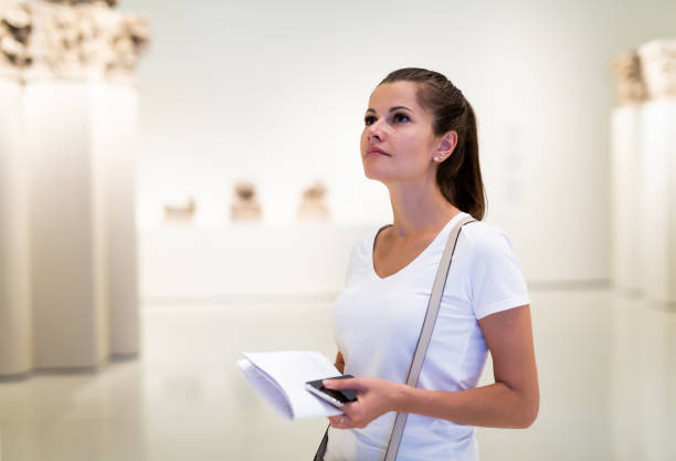 Woman observing sculptures exposition in art museum stock photo