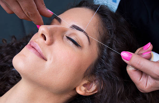 woman on facial hair removal threading procedure stock photo