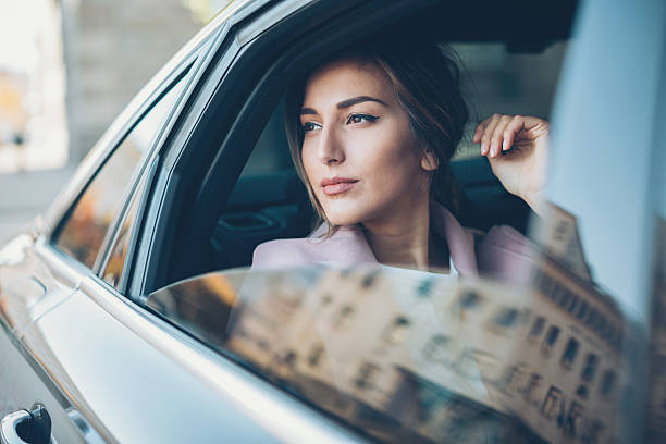 Woman on the back seat of a car Young woman on the back seat of a car looking out of the window. high society stock pictures, royalty-free photos & images