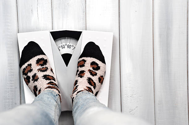 Woman on weight scale in casual clothes stock photo