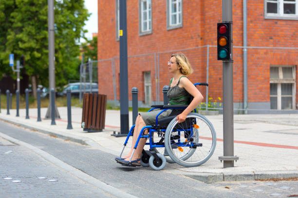 woman on wheelchair crossing the street - wheelchair street imagens e fotografias de stock
