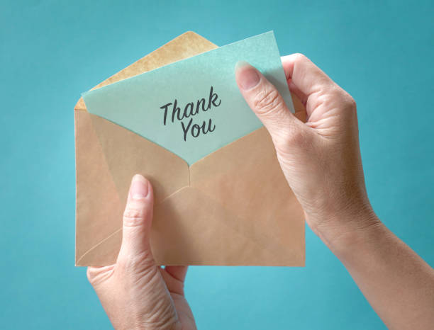Woman open and look at thank you card or note inside a brown envelope. Close up view. stock photo