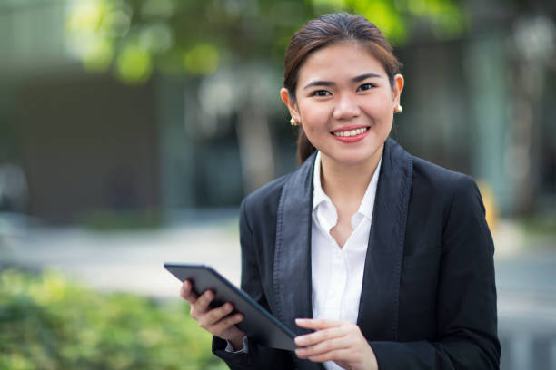 Woman outdoors with a tablet A woman outdoors in an office park holding a tablet computer. filipino woman stock pictures, royalty-free photos & images