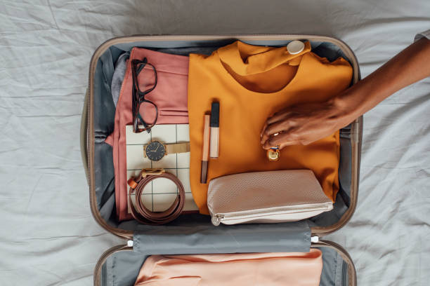 een vrouw die haar kleren in een koffer verpakt - packing suitcase stockfoto's en -beelden
