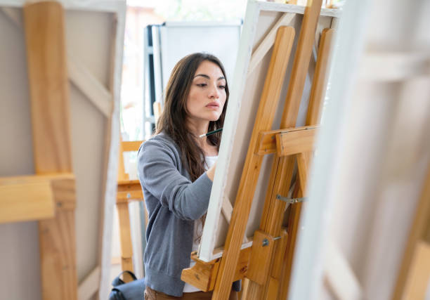 woman painting in an art class - sala de aula universidade arte imagens e fotografias de stock