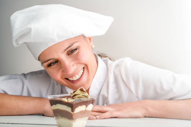 woman pastry chef smiling while observing tiramisu stock photo
