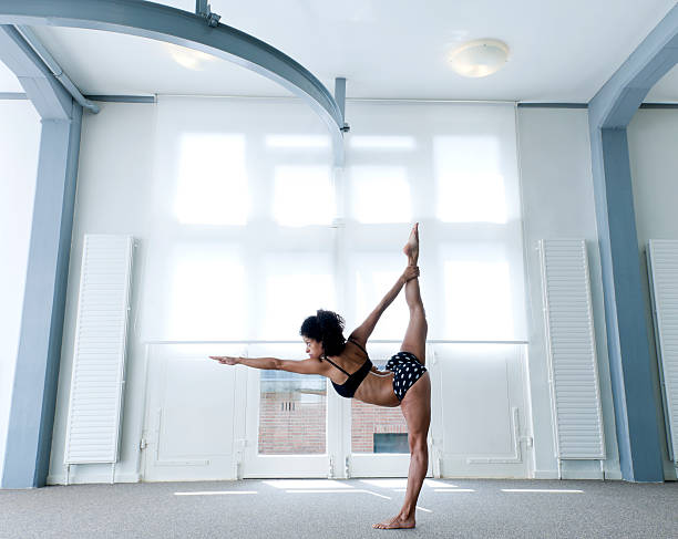 Woman performing standing bow pulling yoga pose - Stok fotoğrafı.