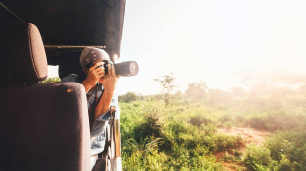 Woman photographer takes a picture with professional camera from touristic vehicle on tropical safari Woman photographer takes a picture with professional camera from touristic vehicle on tropical safari sri lanka women stock pictures, royalty-free photos & images