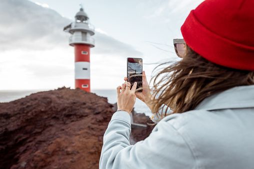 Woman photographing breathtaking views on the rocky coast
