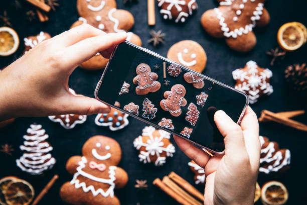 Woman photographing Christmas gingerbread cookies Woman hands photographing beautifully decorated Christmas gingerbread cookies on kitchen counter. Various types of a Christmas cookies on kitchen counter with traditional spices. delicatessen photos stock pictures, royalty-free photos & images