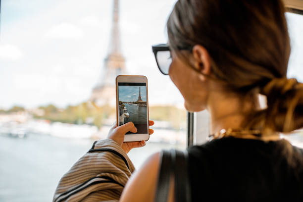 Woman photographing eiffel tower in Paris Young woman photographing with smartphone Eiffel tower from the subway train in Paris. Image focused on the phone eiffel tower paris photos stock pictures, royalty-free photos & images