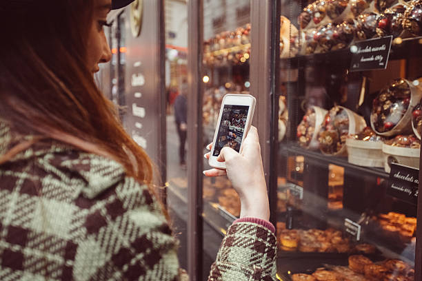 Woman photographing the candy shop window Young woman on a vacation in Paris taking photo of the candy shop baked pastry item photos stock pictures, royalty-free photos & images